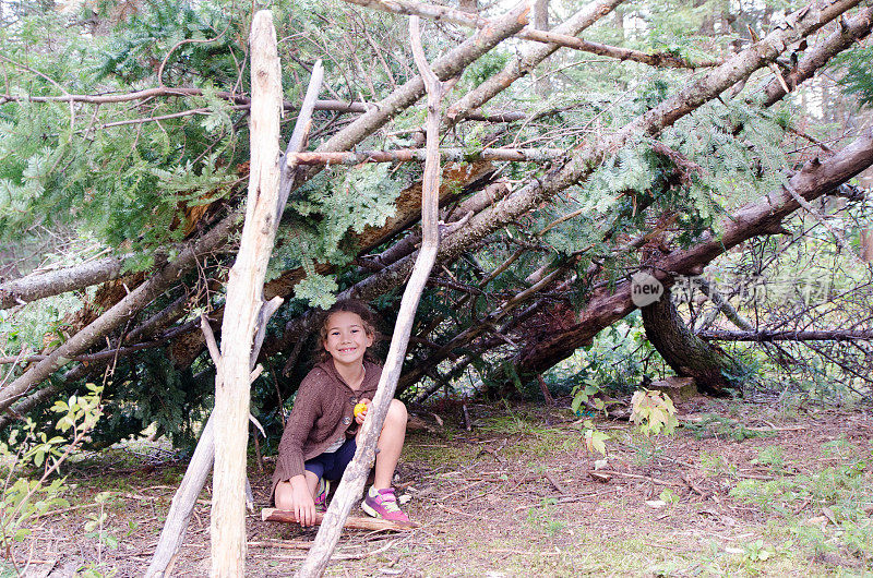 年轻的女孩在他夏天在森林里建造的小木屋里