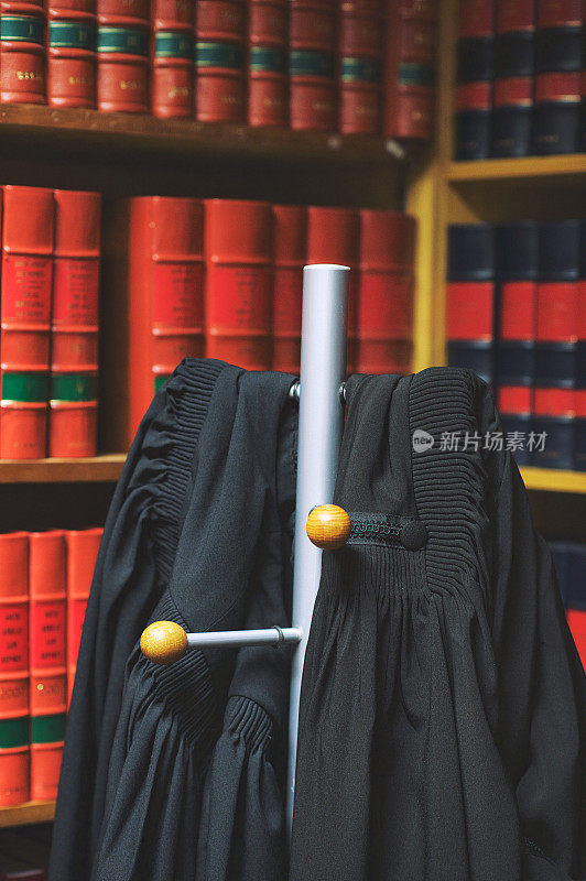 两件黑色律师外套挂在法律图书馆的架子上