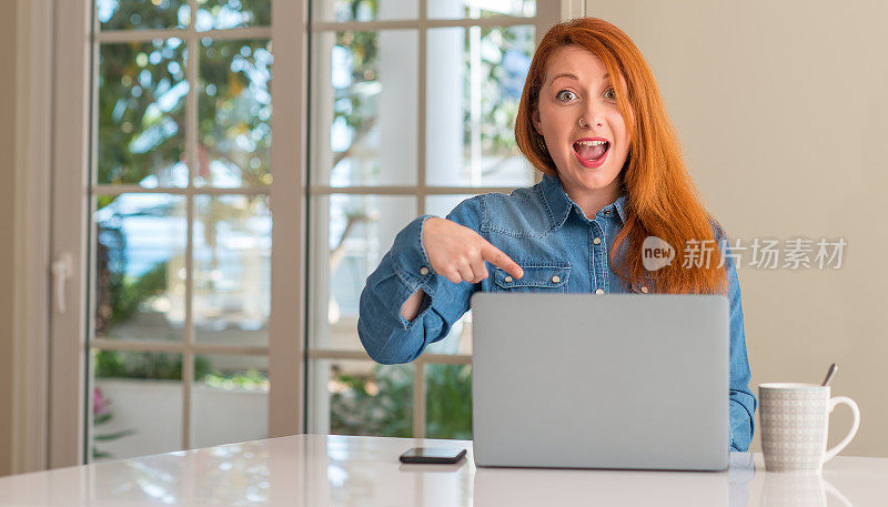 红发女子在家里用手提电脑非常高兴地用手指着
