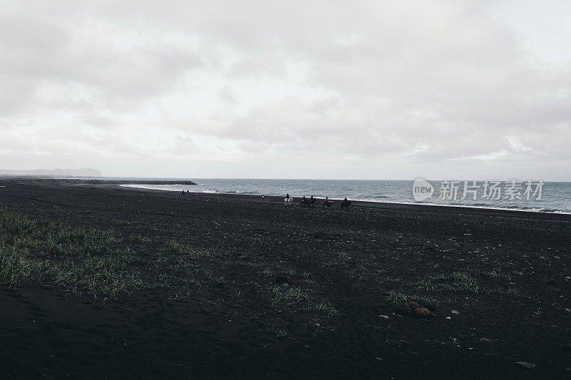 冰岛维克黑沙滩上骑着马的人的剪影
