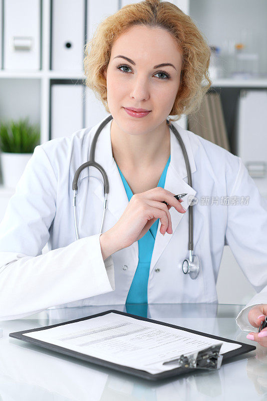 女医生在工作。医生在桌子上填写病史记录表格。医学,医疗保健的概念