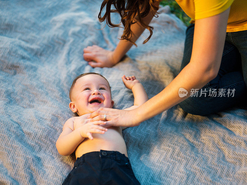 拉丁母亲在挠躺在毯子上的男婴