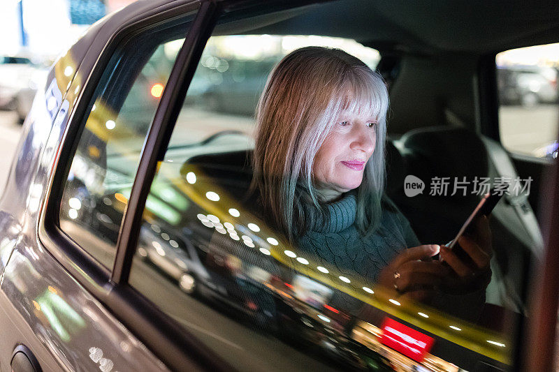微笑的女人在出租车里看智能手机