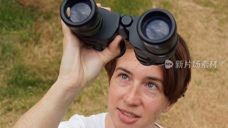 女人正在用双筒望远镜看