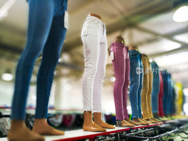 服装店里陈列着色彩鲜艳的时尚女装牛仔裤和长裤