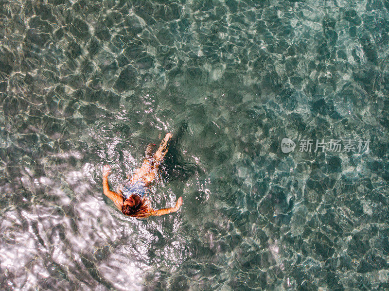 鸟瞰图女人漂浮在清澈的大海