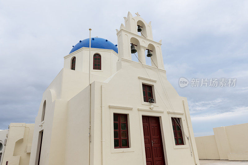 爱琴海圣托里尼岛希腊基克拉迪斯岛伊亚村的一座教堂，粉刷成白色的墙壁和蓝色的圆顶。