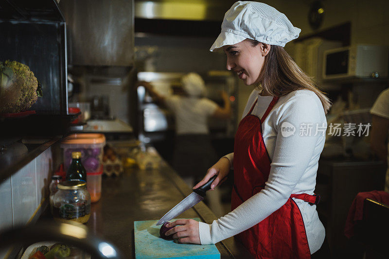 年轻女子在餐厅厨房切菜