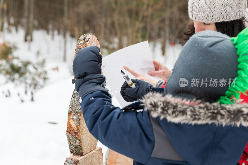 母亲和儿子在冬天户外做一个木制雪人