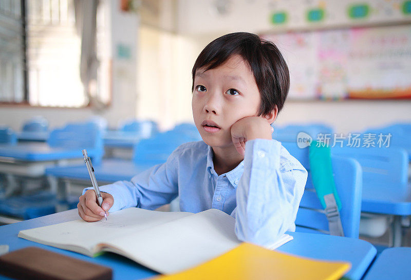 小男孩在教室里的书桌前读书