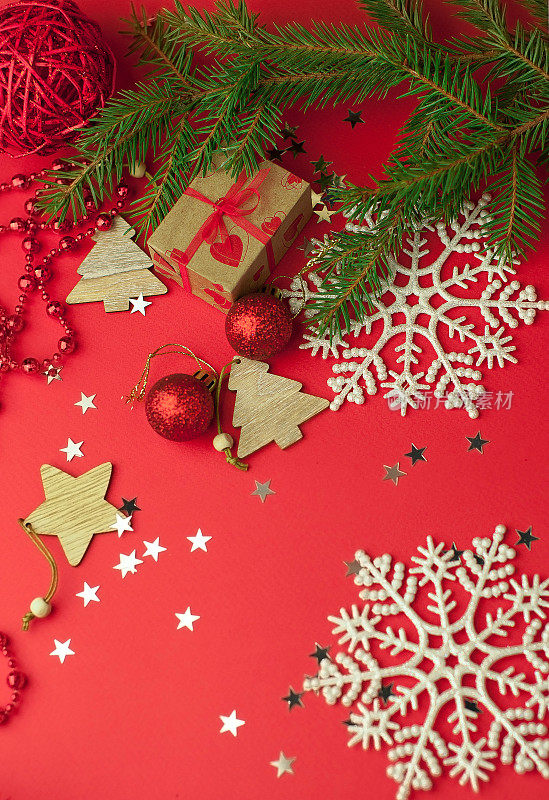圣诞喜庆的红色背景与冷杉枝，下面是礼物在牛皮纸圣诞装饰品，玩具和雪花