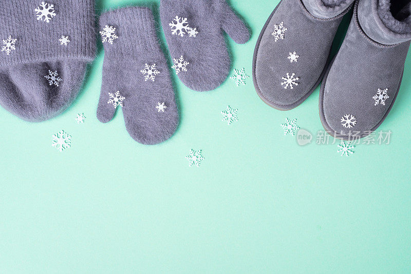 冬天暖和的衣服平躺着。羊毛女装毛衣，围巾，靴子，蓝色背景的雪花。俯视图，复制空间