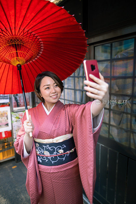 穿着和服的年轻女子在一家旧零售店前自拍