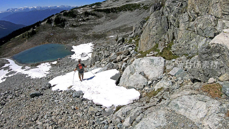 徒步旅行者沿着积雪的山坡跑下去