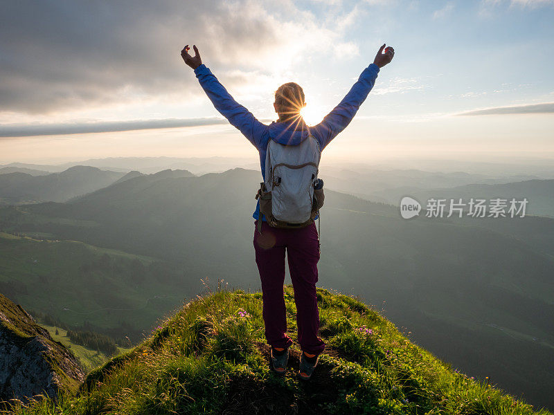 山顶上的女人张开双臂拥抱自由和自然