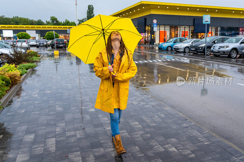 年轻女子撑着黄伞在雨中行走