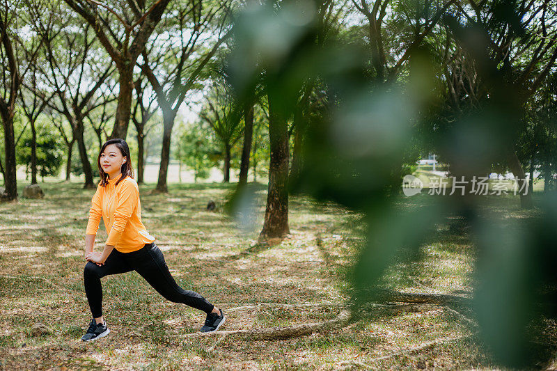 运动的亚洲华人妇女伸展她的腿和做热身运动