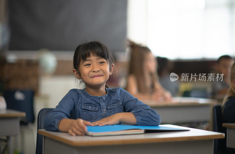 可爱的女孩在她的课桌上微笑