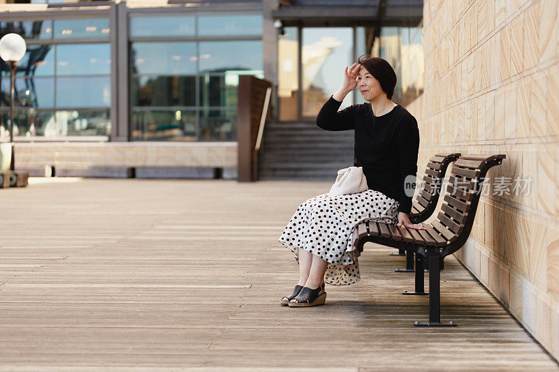 笑容可掬的日本女子坐在长凳上，望向远方