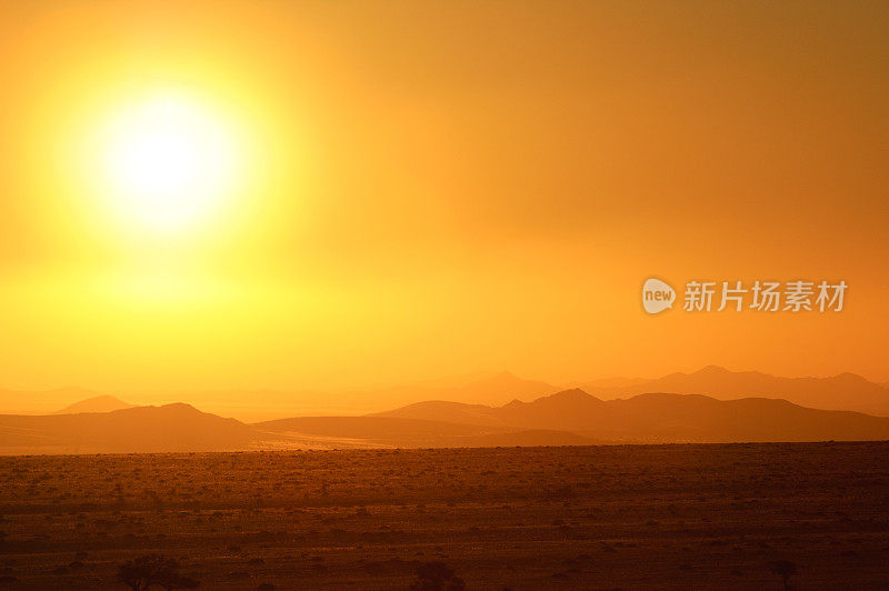 沙尘暴过后，纳米比亚沙漠上空傍晚时分的太阳和橙色的天空