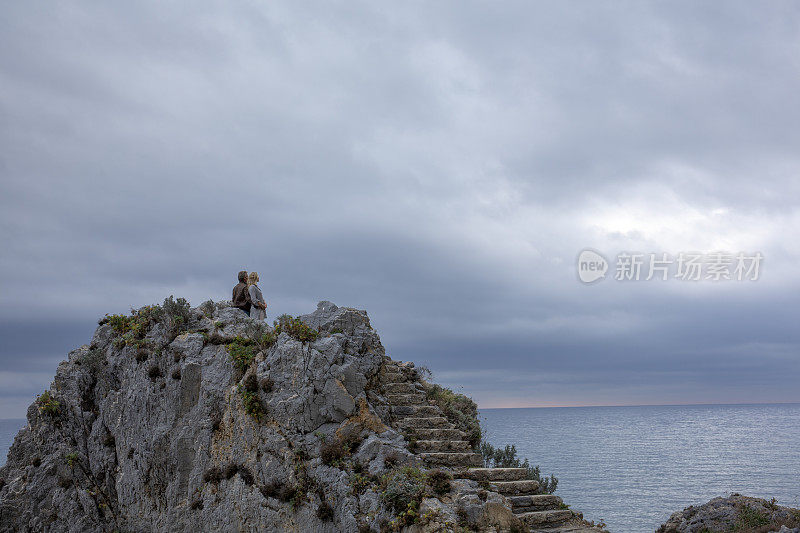 清晨，一对成熟的夫妇走上楼梯，来到海边的岩石上