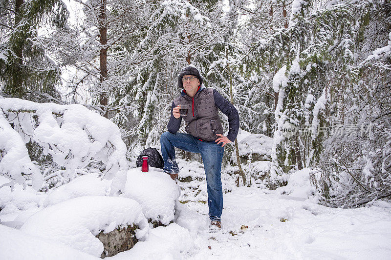 白种人在冬天的雪地里。那个人正在休息和喝咖啡。步行旅游。