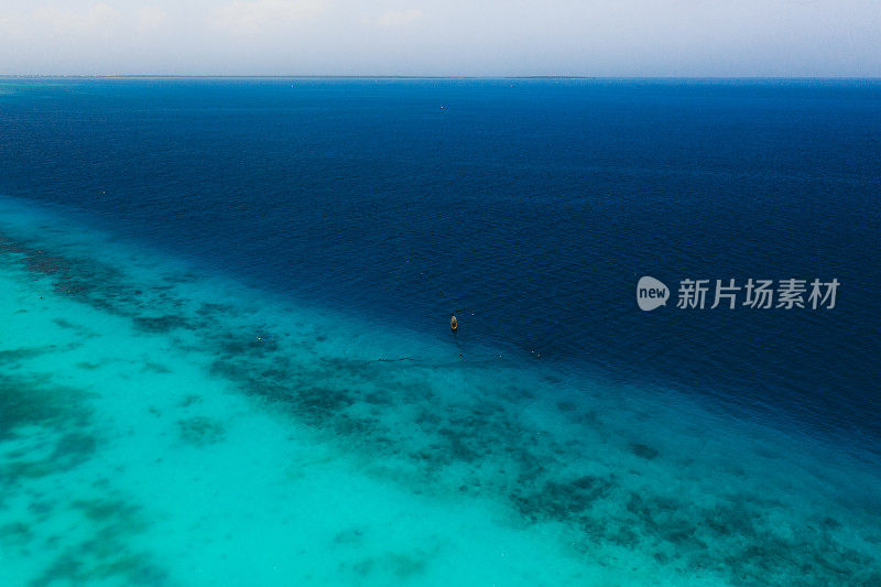 高角度鸟瞰图上的孤独的老木制渔船在纯绿松石的海洋上，坦桑尼亚桑给巴尔岛