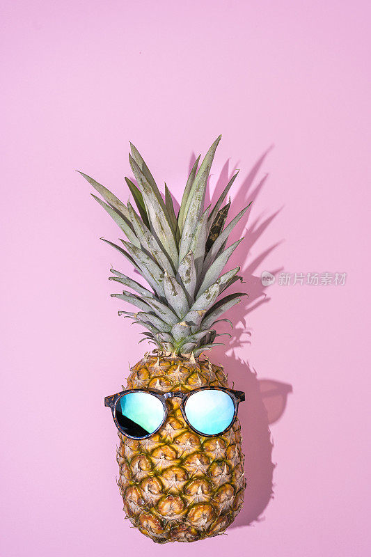 夏天在派对上。潮人菠萝时尚太阳镜和音乐明亮美丽的色彩在假日，创造性的艺术水果为热带风格的海滩氛围，粉红色的背景。时尚暑期概念