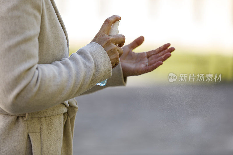 一个女人在用消毒喷雾喷她的手