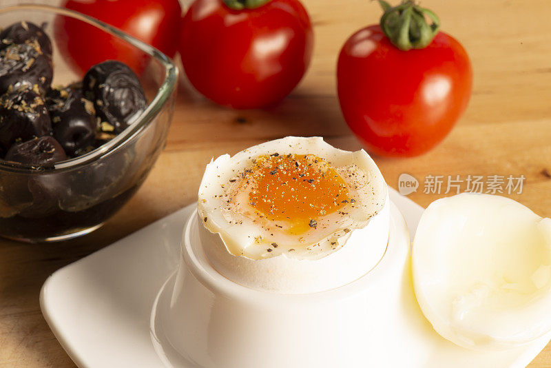 水煮鸡蛋配黑胡椒是在餐桌上与橄榄和番茄横拍留念