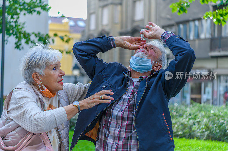 一位有眼病的老人在细心的妻子的帮助下滴眼药水。