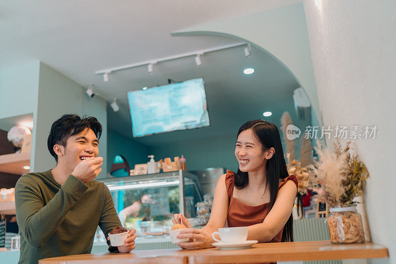 年轻的亚洲情侣在咖啡馆边吃冰淇淋边约会