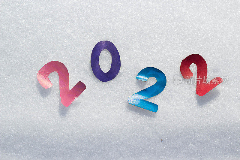 在雪地上用彩色字母写下2022。自然纹理的新年设计