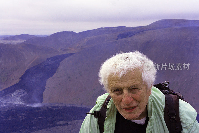 冰岛Fagradalsfjall火山上的老人，背景是冷却的熔岩外壳