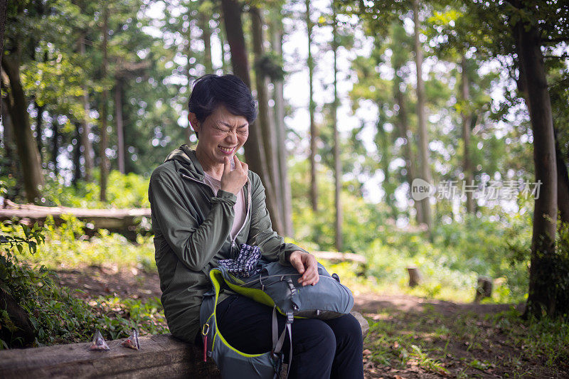 日本女人坐在原木上，吃着咸李子在森林里