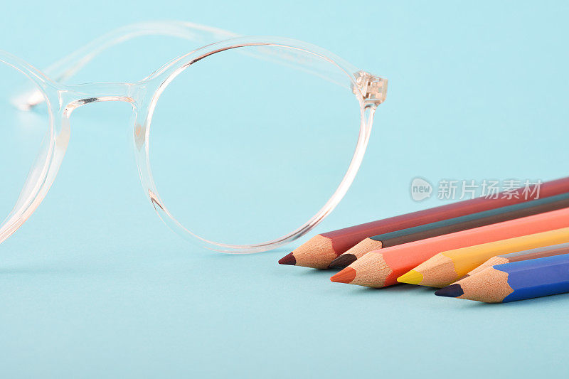 一副眼镜，蓝色背景上有彩色铅笔