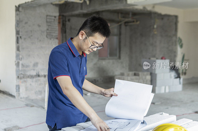 亚洲男性工程师在装修工地处理施工图纸