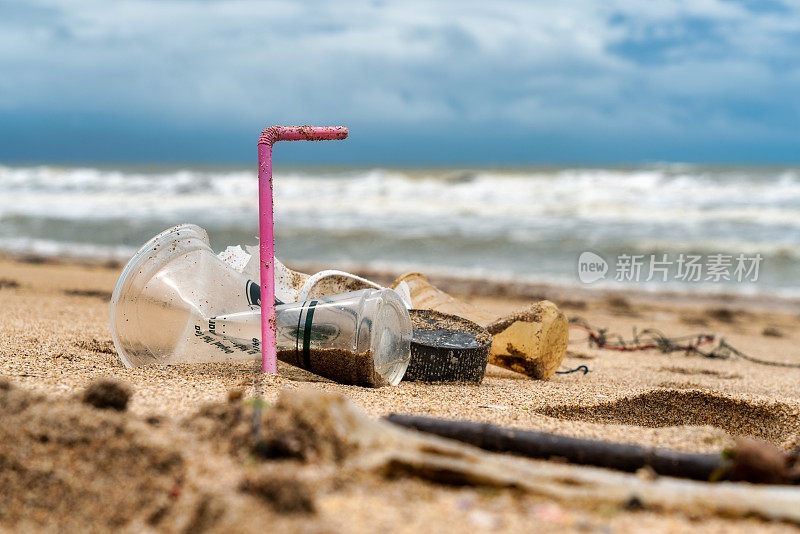 废弃的塑料杯和污染海滩的稻草
