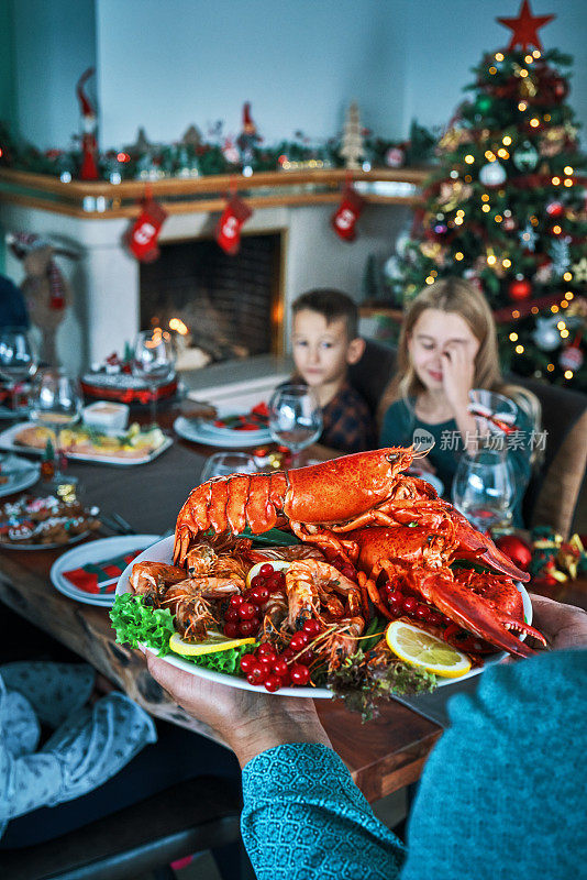 全家享用圣诞晚餐，有三文鱼片，扇贝，龙虾，虾和圣诞蛋糕
