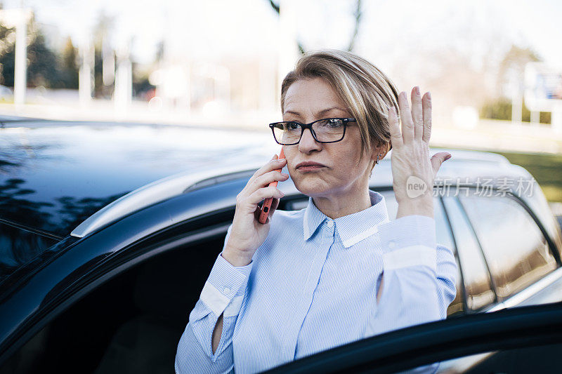 成熟的女人站在车旁。