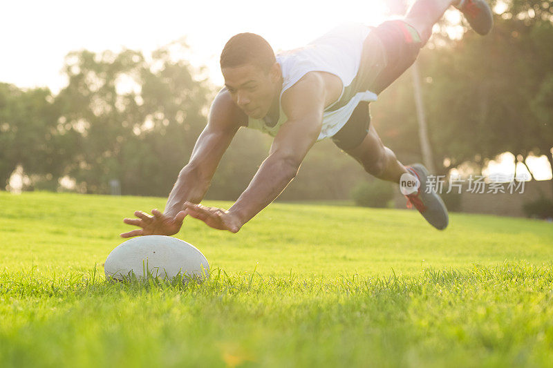 动作中的橄榄球运动员扑向地面去抢场上的球。