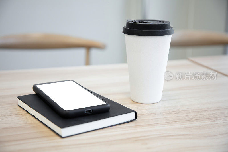 咖啡桌上放着一部空白屏幕的智能手机