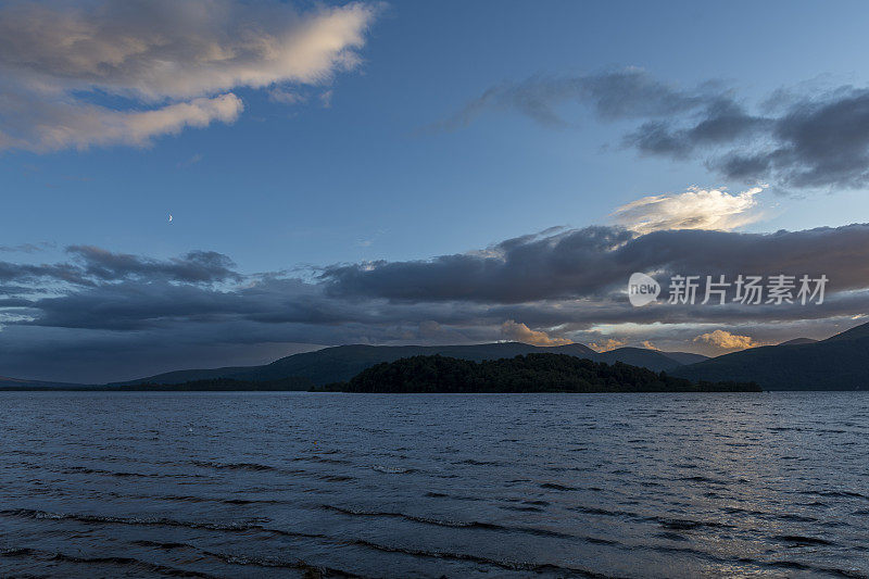 在英国苏格兰的洛蒙德湖沿岸，日落在群山之上。