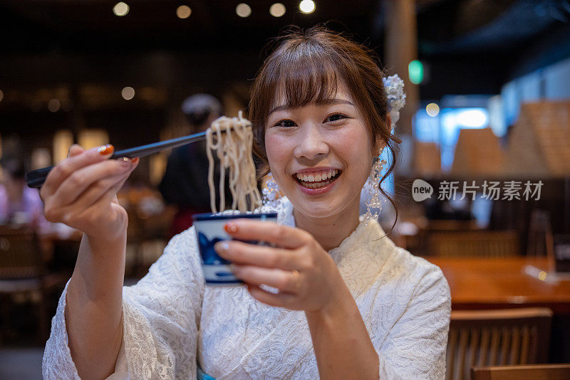 快乐的女人在白色蕾丝和服显示荞麦在日本餐厅午餐