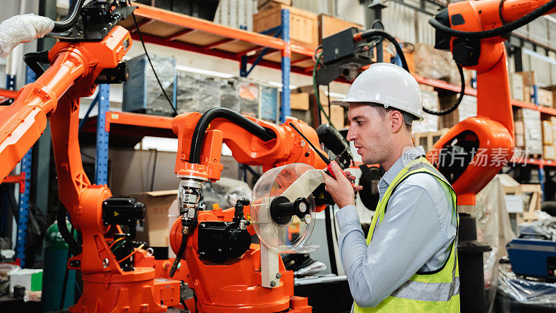 工业工程师在工业制造工厂控制自动臂机焊接机器人。