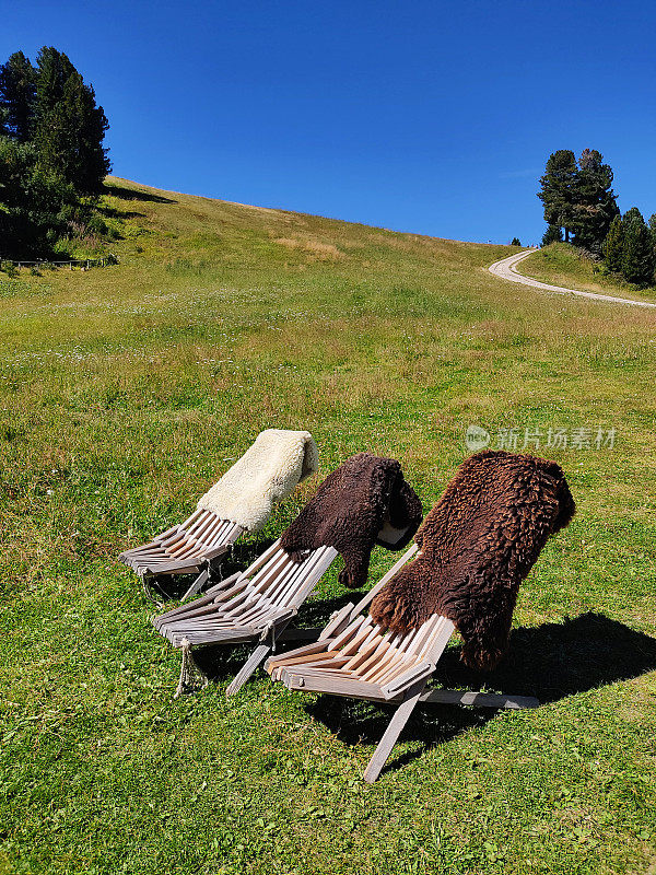 三张木质躺椅放在草地上，皮草铺在意大利白云石上