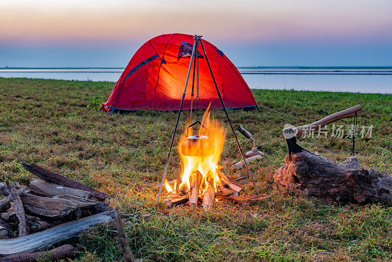 在湖边草地上的橙色帐篷里营火