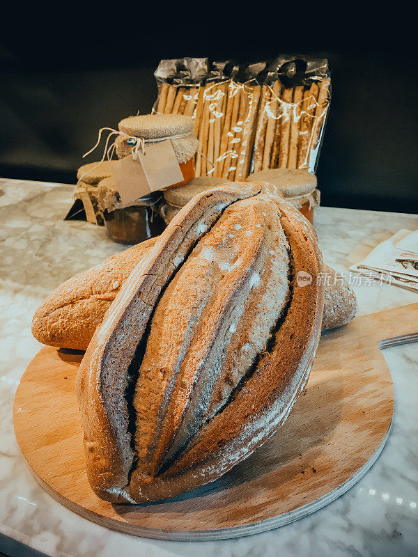 桌子上装饰着各种手工制作的面包，现烤手工酵母面包，静物面包和小麦，工厂用于生产烘焙产品，查看各种面包