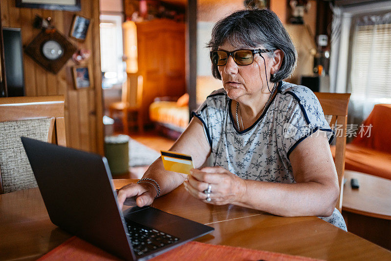 老年妇女在家用笔记本电脑网购