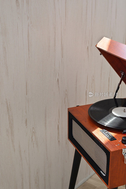 棕色复古木制唱盘与灰黑胶唱片室内中性米色墙壁背景，复制空间。现代潮流，数字黑胶播放器，家庭内部。怀旧音乐风格概念
